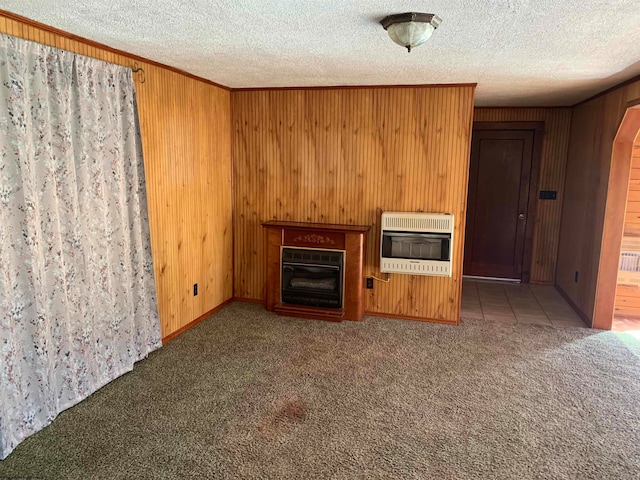 unfurnished living room with wood walls, a textured ceiling, heating unit, and carpet floors