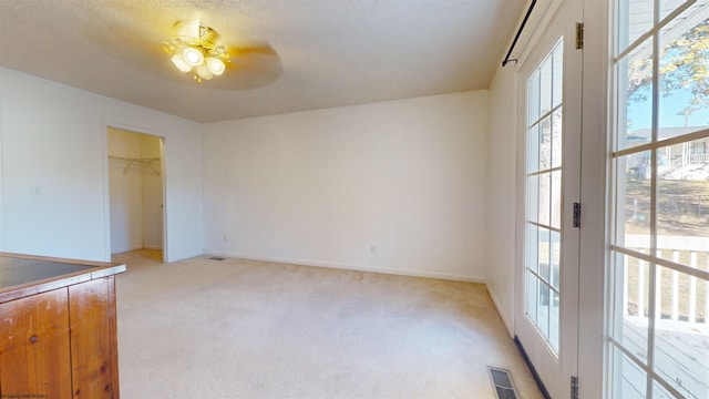 unfurnished room featuring light carpet, ceiling fan, and a wealth of natural light