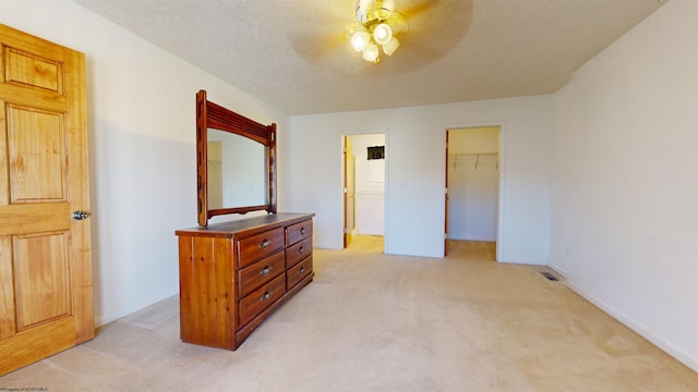 carpeted bedroom featuring a closet, ceiling fan, a textured ceiling, and a walk in closet