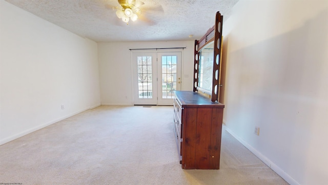 carpeted empty room featuring french doors, a textured ceiling, and ceiling fan