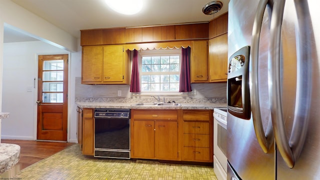 kitchen with black dishwasher, sink, light hardwood / wood-style floors, white range oven, and stainless steel fridge with ice dispenser