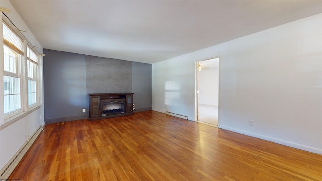 unfurnished living room featuring hardwood / wood-style floors, a baseboard heating unit, and a tile fireplace