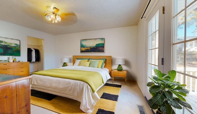 carpeted bedroom featuring a closet, a textured ceiling, a spacious closet, and ceiling fan