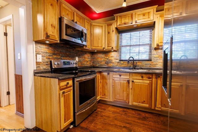 kitchen with sink, crown molding, appliances with stainless steel finishes, and dark hardwood / wood-style flooring