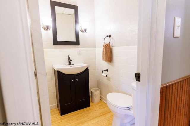 bathroom featuring vanity, hardwood / wood-style flooring, toilet, and tile walls