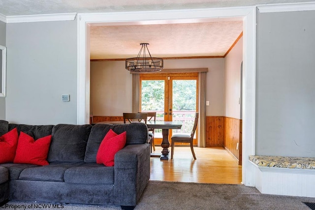 living room with wood walls, french doors, a textured ceiling, crown molding, and hardwood / wood-style flooring