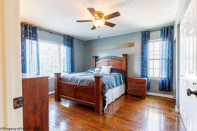 bedroom featuring dark wood-type flooring, a textured ceiling, a closet, and ceiling fan