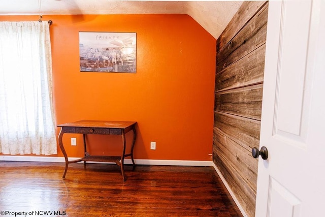 empty room featuring wood-type flooring and vaulted ceiling