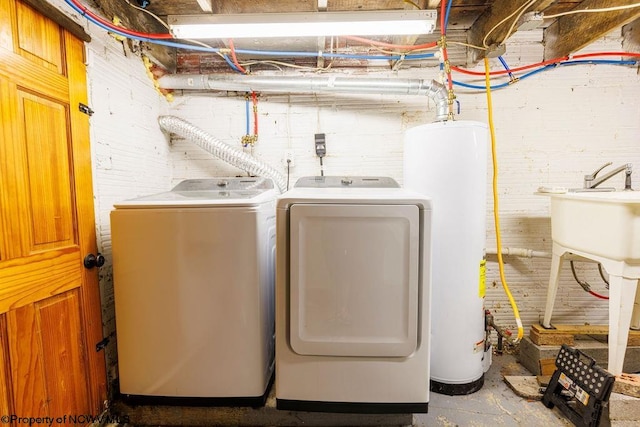 clothes washing area featuring gas water heater and washer and clothes dryer