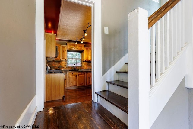 staircase with a textured ceiling, sink, and wood-type flooring