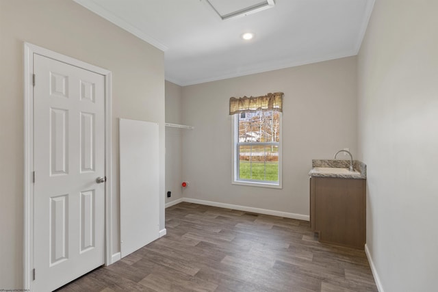 interior space with baseboards, wood finished floors, crown molding, and a sink