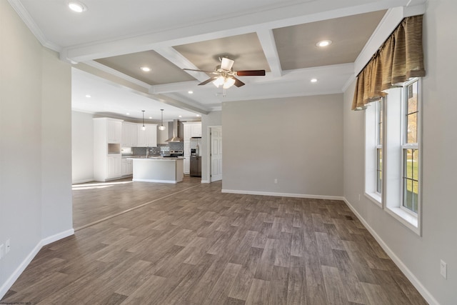 unfurnished living room with coffered ceiling, beamed ceiling, wood-type flooring, ornamental molding, and ceiling fan