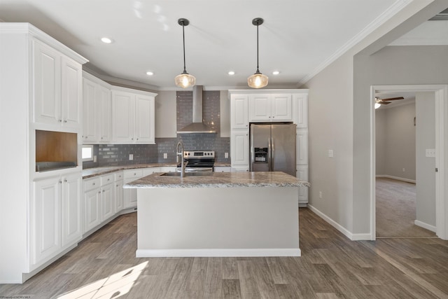 kitchen featuring wall chimney range hood, decorative backsplash, appliances with stainless steel finishes, ornamental molding, and a kitchen island with sink