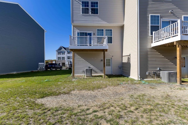 rear view of house with central AC, a lawn, and a balcony