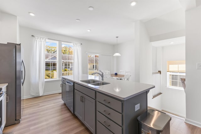 kitchen featuring a center island with sink, gray cabinetry, decorative light fixtures, and light hardwood / wood-style floors