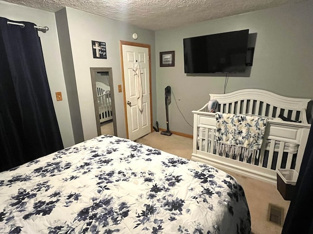 bedroom with light colored carpet and a textured ceiling