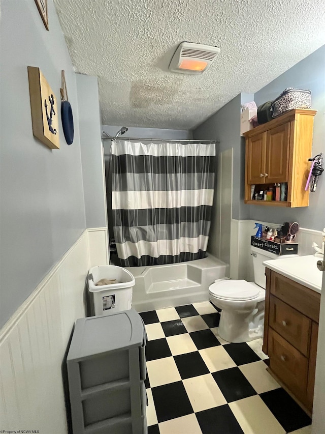 full bathroom featuring vanity, shower / bath combination with curtain, a textured ceiling, and toilet