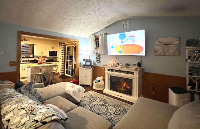 living room with hardwood / wood-style floors, lofted ceiling, and a textured ceiling