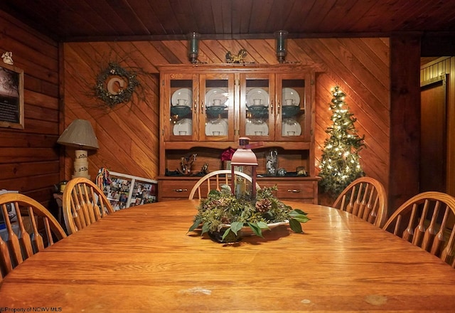 dining room featuring wood ceiling and wooden walls