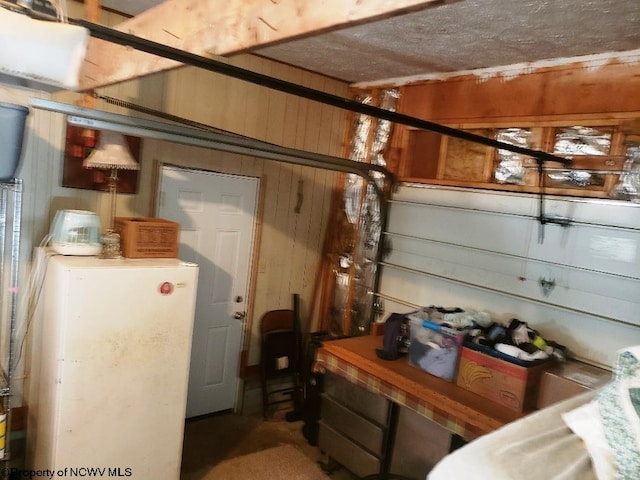 interior space with white refrigerator and wood walls