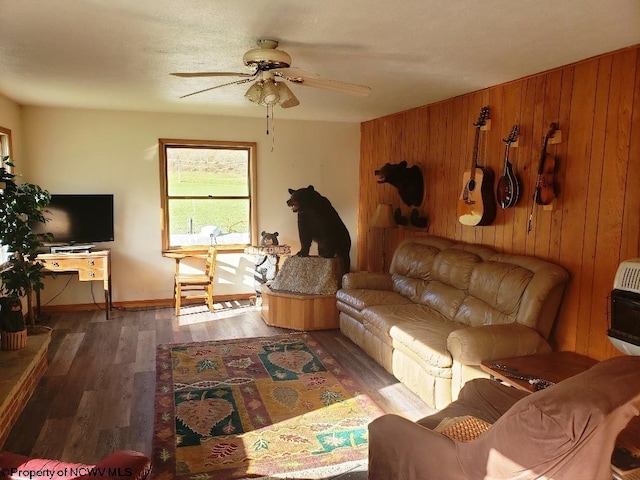 living room featuring ceiling fan, wood walls, dark hardwood / wood-style flooring, and heating unit