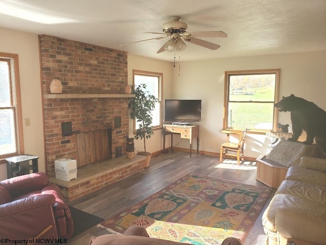 living room with dark wood-type flooring, ceiling fan, plenty of natural light, and a fireplace