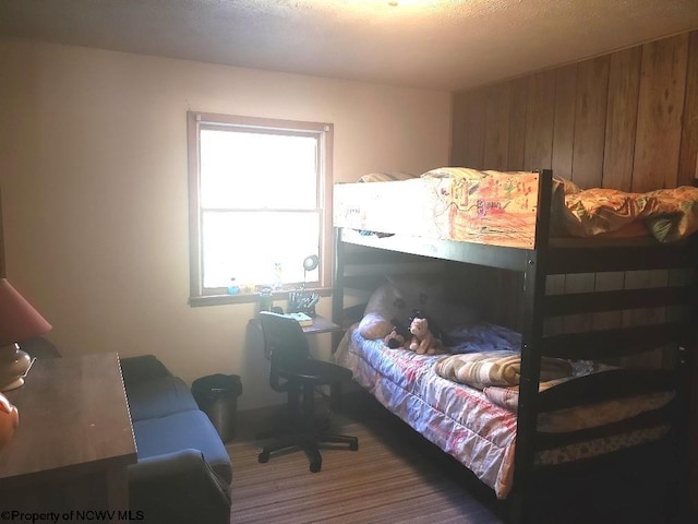 bedroom with wooden walls and a textured ceiling