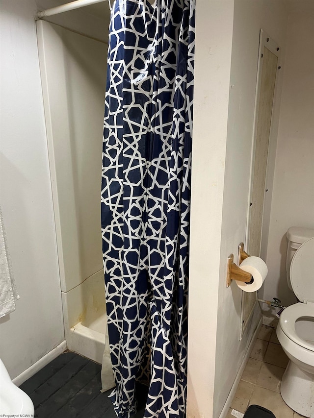 bathroom with toilet, walk in shower, and tile patterned floors