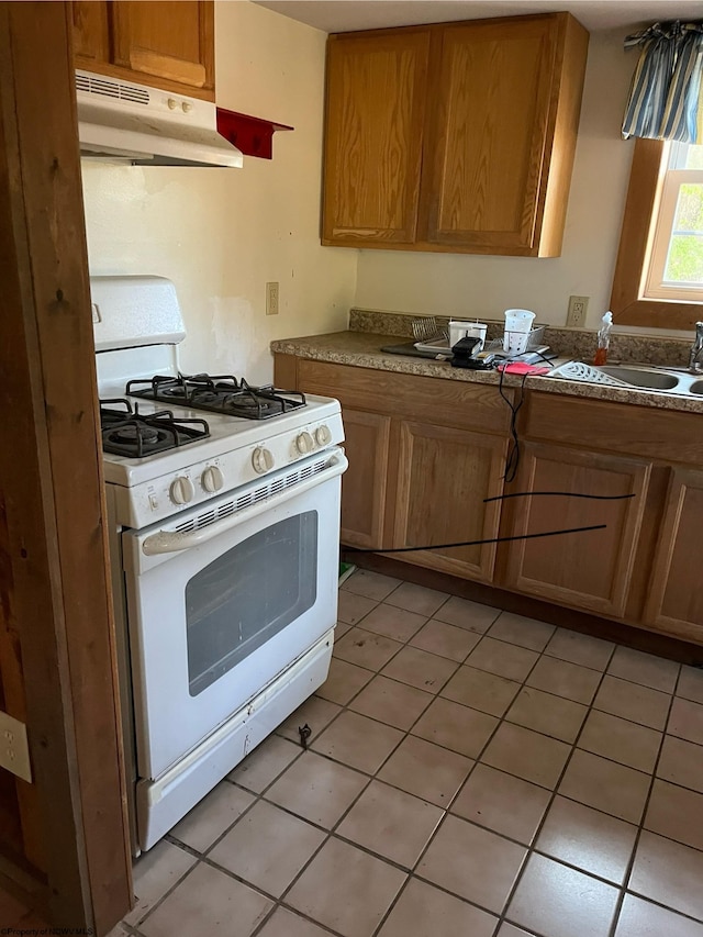 kitchen featuring sink, white gas range oven, and light tile patterned floors