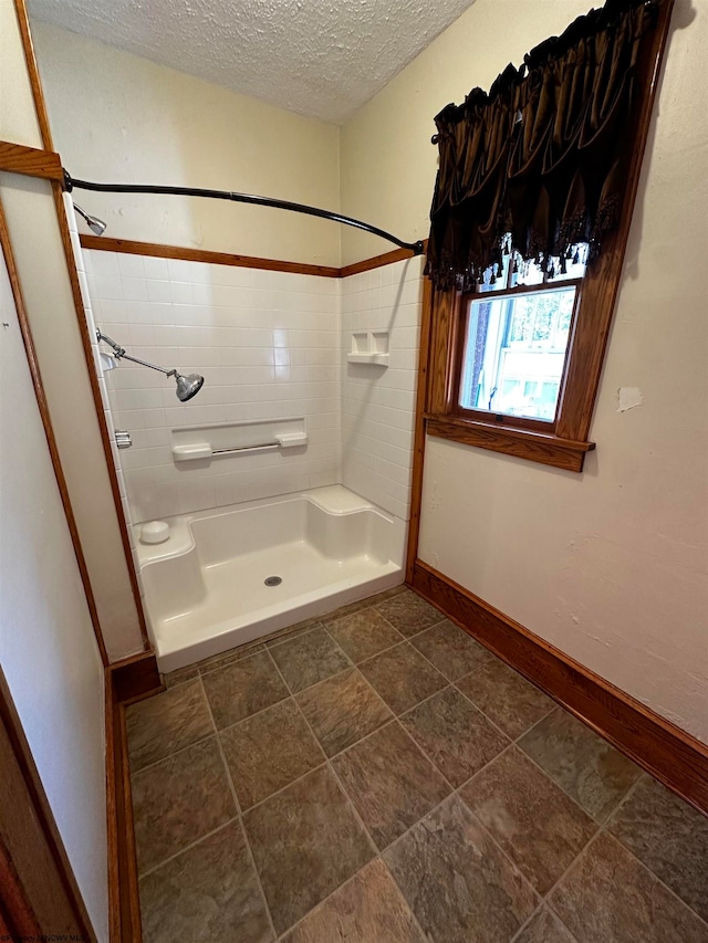 bathroom with a shower, a textured ceiling, and tile patterned flooring