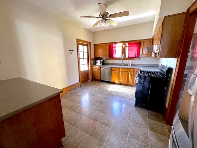 kitchen featuring exhaust hood, ceiling fan, a textured ceiling, sink, and stainless steel appliances