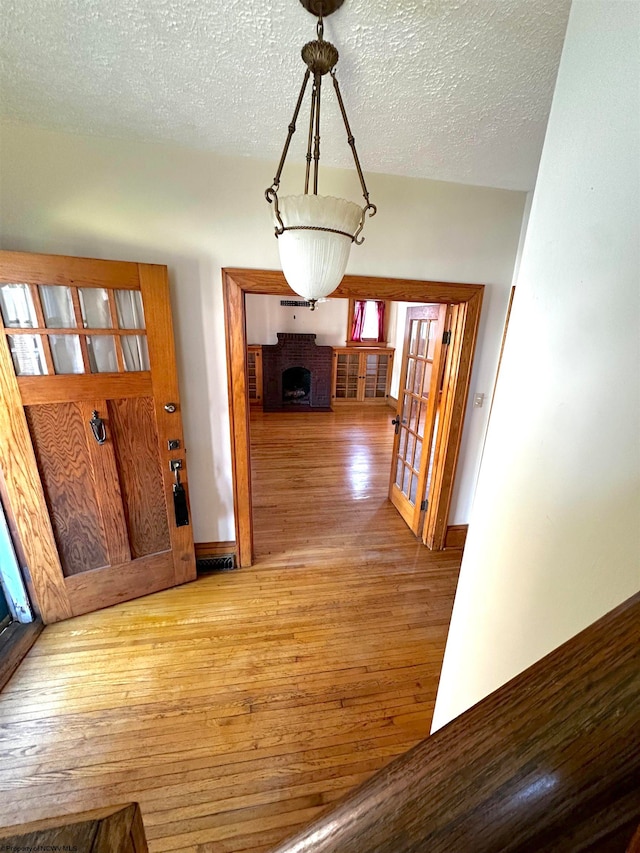 interior space featuring light hardwood / wood-style flooring, a brick fireplace, and a textured ceiling