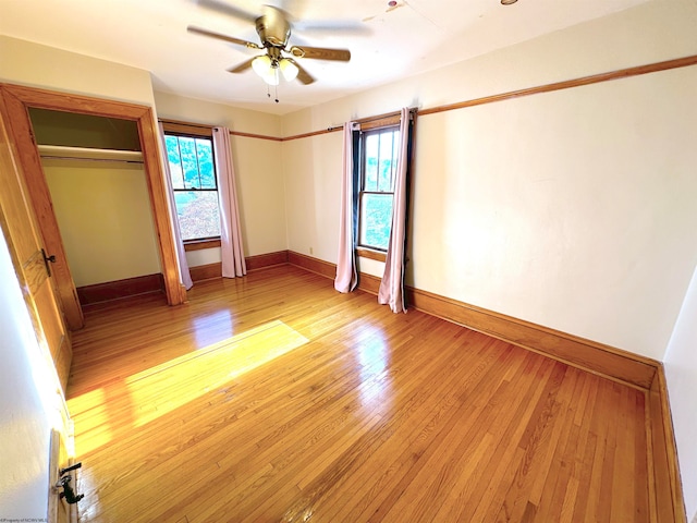 unfurnished bedroom with a closet, multiple windows, light wood-type flooring, and ceiling fan