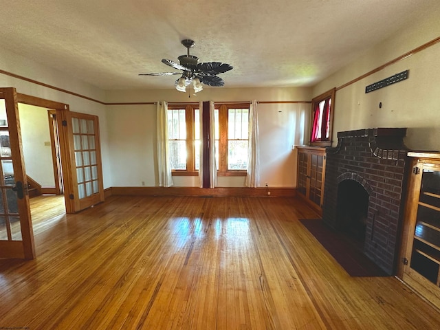 unfurnished living room featuring hardwood / wood-style floors, a textured ceiling, a fireplace, and ceiling fan