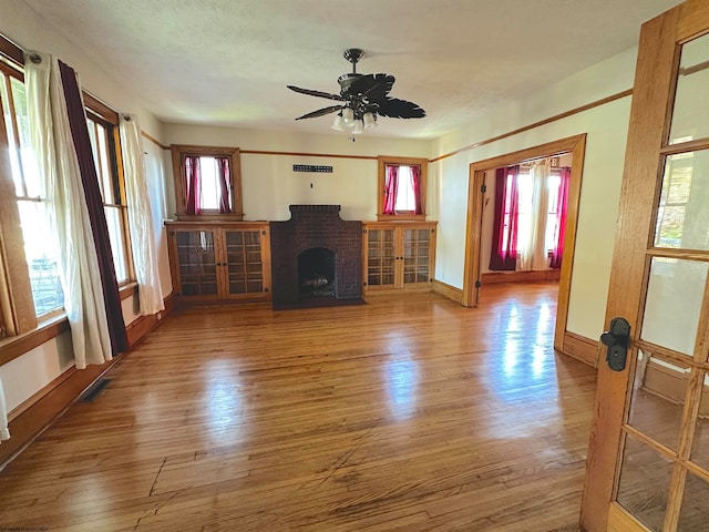 unfurnished living room with a brick fireplace, wood-type flooring, and a healthy amount of sunlight