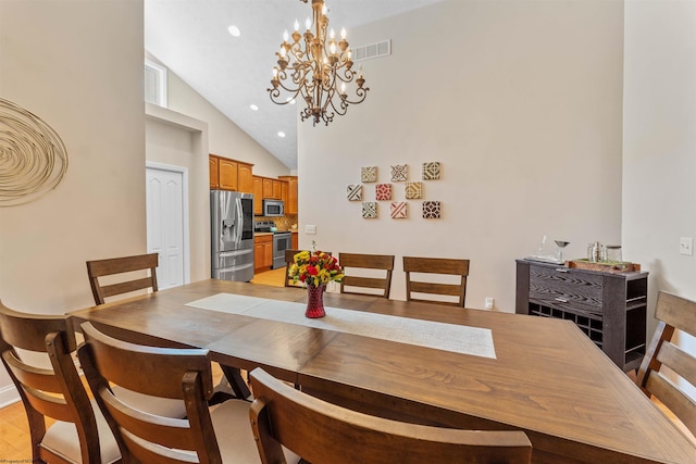 dining room with light hardwood / wood-style flooring, high vaulted ceiling, and an inviting chandelier