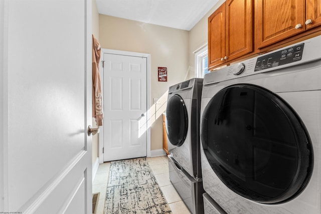 laundry room featuring independent washer and dryer, light tile patterned floors, and cabinets