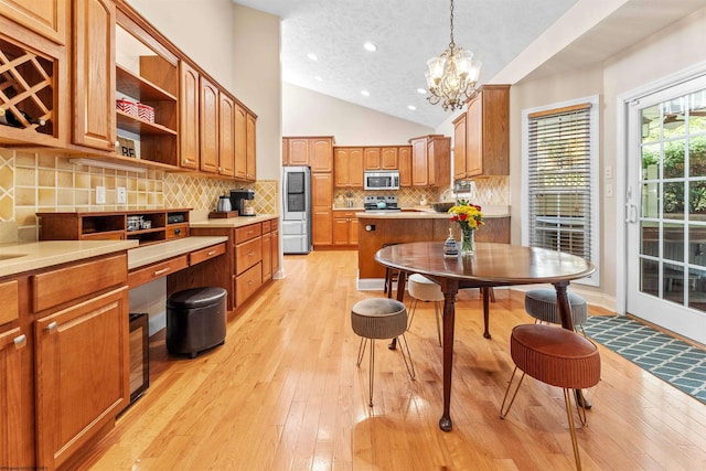 kitchen with tasteful backsplash, a textured ceiling, stainless steel appliances, vaulted ceiling, and pendant lighting