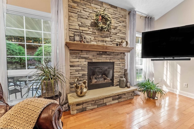 living room featuring hardwood / wood-style floors, a textured ceiling, a fireplace, and vaulted ceiling