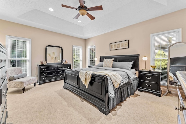 bedroom with multiple windows, a tray ceiling, and ceiling fan