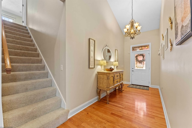 entrance foyer with high vaulted ceiling, hardwood / wood-style flooring, and an inviting chandelier