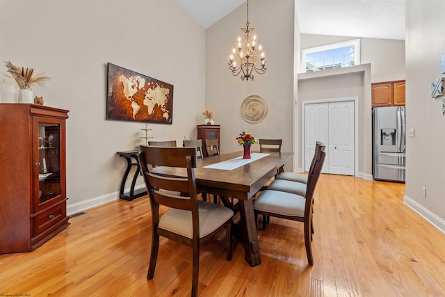 dining space with light hardwood / wood-style flooring, a chandelier, and high vaulted ceiling