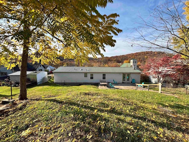 rear view of property featuring a yard, a shed, and a patio area