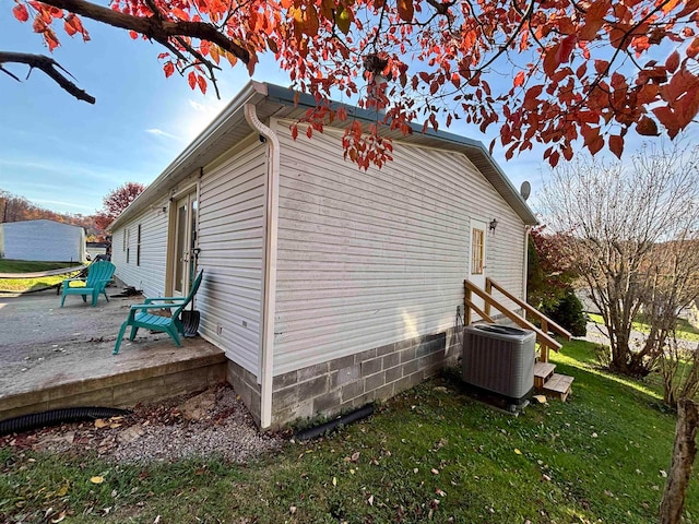 view of side of home featuring a yard, a patio, and central AC unit