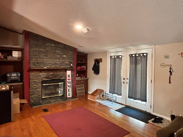 living room featuring lofted ceiling, wood-type flooring, a textured ceiling, and a fireplace