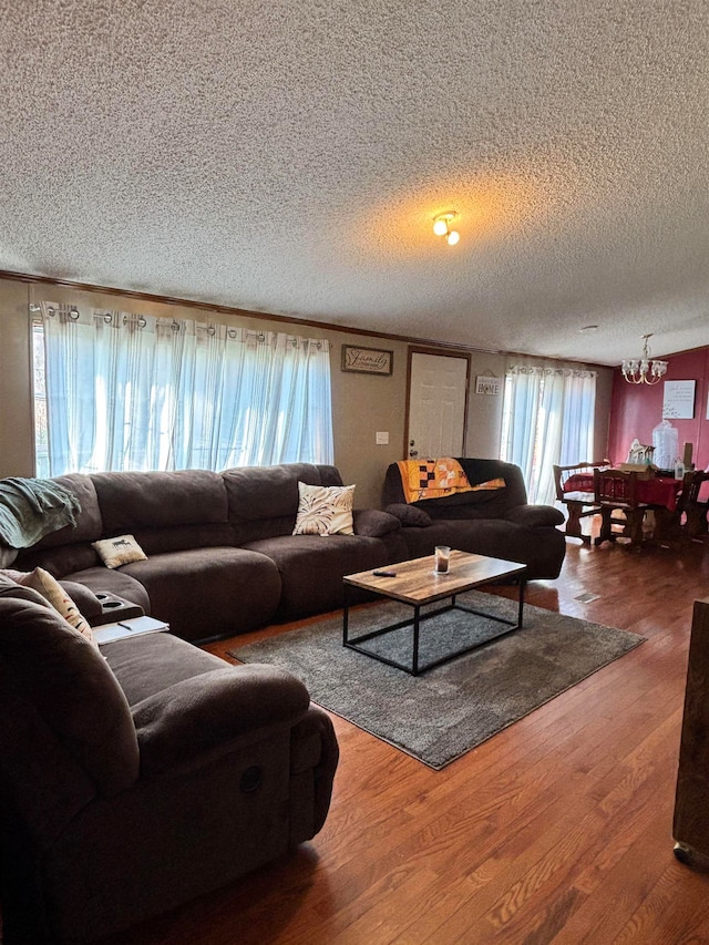 living room with hardwood / wood-style floors, a textured ceiling, and an inviting chandelier