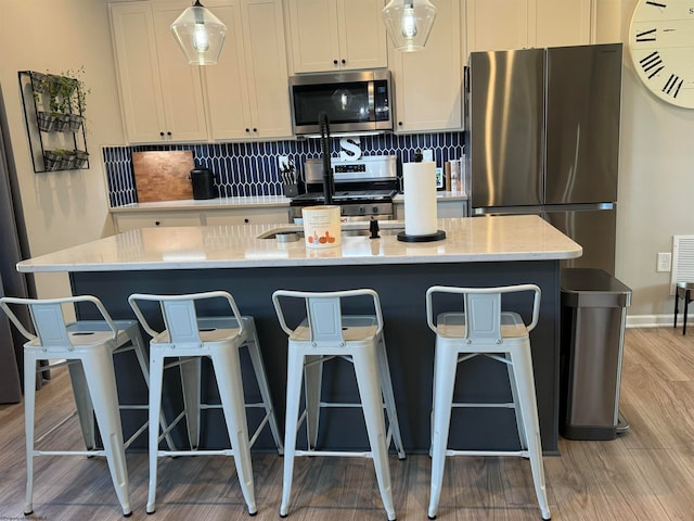 kitchen featuring a center island with sink, appliances with stainless steel finishes, and tasteful backsplash