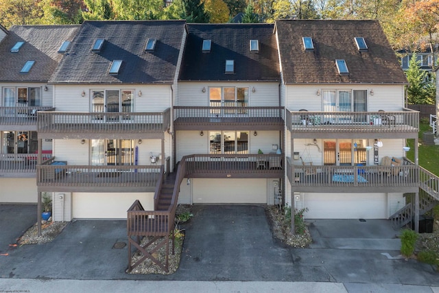 back of property with driveway, stairs, a balcony, roof with shingles, and a garage