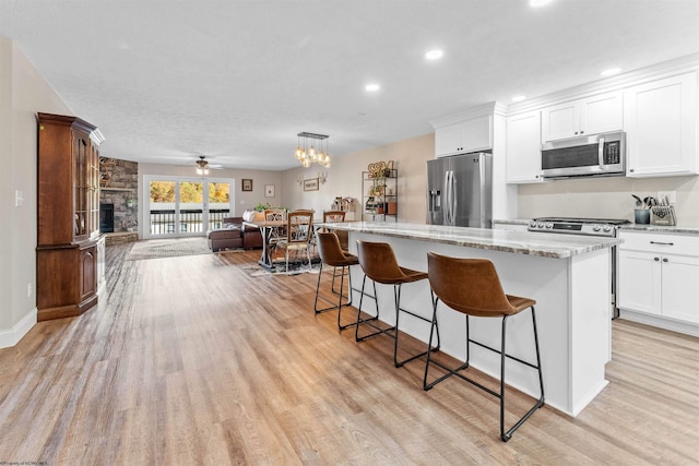 kitchen featuring light wood-style floors, a center island, a breakfast bar area, appliances with stainless steel finishes, and open floor plan