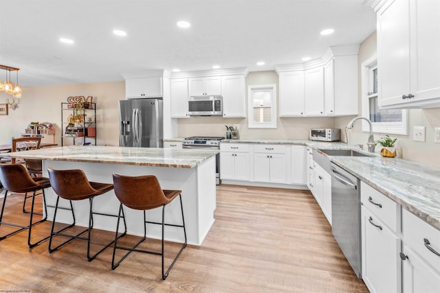 kitchen featuring a breakfast bar area, a center island, appliances with stainless steel finishes, and white cabinets